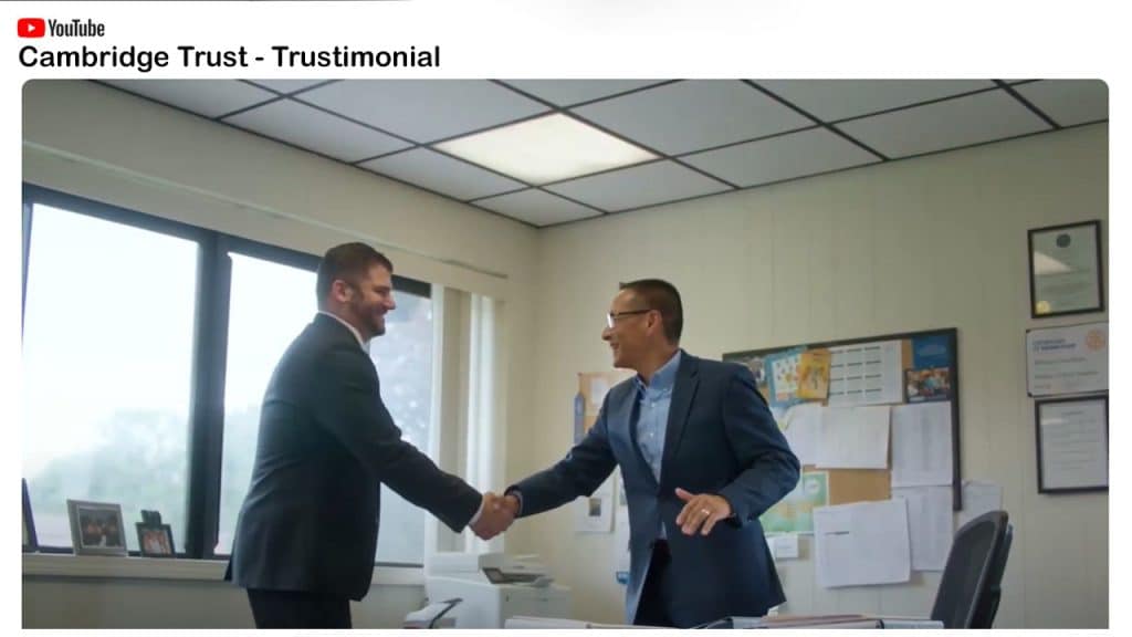 Two men standing in an office and shaking hands while smiling