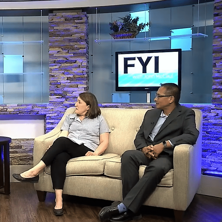 A woman and a man sitting on a couch and looking to the left of the frame