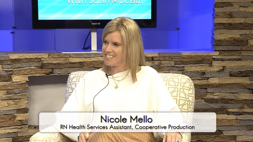 A blond woman in a white shirt sitting in a comfortable chair is looking to the left of the frame